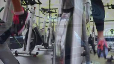 El pedala uzanıyor ve pedal çeviren iki kadın spor için ritmi artırıyor. İkili, kardiyo, stüdyo, gün ışığı, odaklanma, dayanıklılık, motivasyon