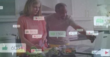 Kadın sebze doğrarken, sosyal medya bağlantısını takip ederken erkek bilgisayara dokunuyor ve onu işaret ediyor. Çift, mutfak, ada, sebze, salata, bilgisayar, kaplamalar