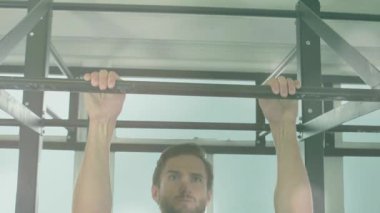 Barfiks çubuğunu kavramış ve fitness için çekmeye başlamış, kamera üst tutucuları çekiyor ve aşağı iniyor. Spor, egzersiz, güç, eğitim, atletik, odaklanma, kararlılık