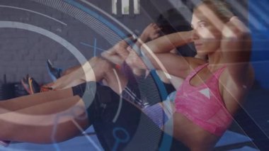 Çekirdek zindeliği için bükülmeye başlayan bir kadın, mavi paspaslar üzerinde grup senkronizasyonu, kareye yayılan HUD. Sınıf, egzersiz, rotasyon, gövde, hareket, kaplama, stüdyo