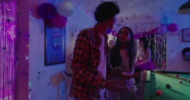 Ekose adam ve çizgili kadın kollarına dokunuyor, süs eşyalarına yürüyor, pasta düzenliyor, parti ışıkları parlıyor. Kutlama, disko, dekor, balonlar, neon, gökkuşağı, fıçı