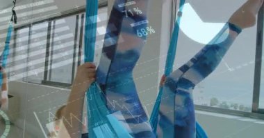 Sapanı tutan, tırmanan ve ters çeviren bir kadın. Sonra destek vermeye dönen bir kadın. Fitness HUD grafikleri gösteriyor. Hava, hamak, ikili, stüdyo, egzersiz, askıya alınmış, ters çevrilmiş