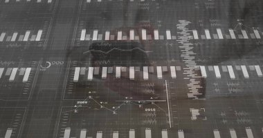 Ofis camında dijital gösterge paneli gösteriliyor, çizelgeler ve koyu renk cekette soluk bir yansıma görülüyor. Panel, grafikler, veri, analitik, monokrom, dokunmatik ekran, ızgara çizgileri