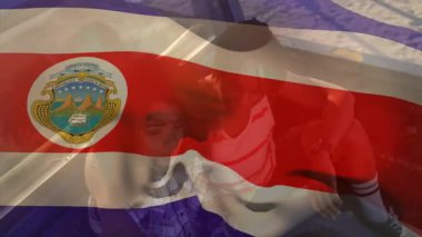 Kosta Rika bayrağının Afrika kökenli Amerikalı bir çiftin sahilde kamyonet bagajında sallanışının animasyonu. Dijital bileşim, seyahat, yolculuk, aşk, birliktelik, tatil, vatanseverlik ve kimlik.. .