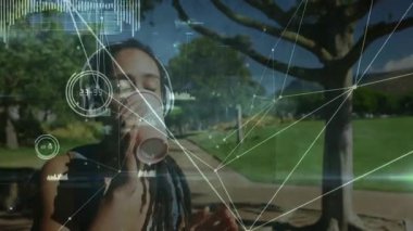 Kulaklık takan, kahve yudumlayan, sağlık kontrolü için biyometrik veri örtüsü yapan bir kadın. Teknoloji, sağlık, bağlantı, açık hava, sakinlik, yenilik, rahatlama.