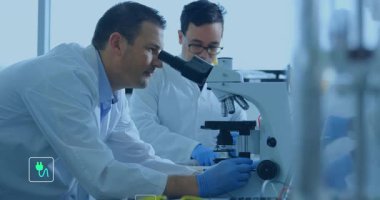 Araştırma laboratuvarındaki bilim adamları mikroskop etrafında yüzen enerji simgelerini görüntülemek için odak ayarlıyorlar. Araştırma, yenilik, teknoloji, işbirliği, bilim, laboratuvar, deney