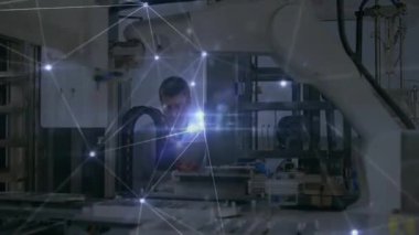 Mühendis, kontrol panelleri üzerinde parlayan ağ örtüsünü gösteren robotik hücreyi denetleyen tablet kullanıyor. Otomasyon, üretim, bağlantı, teknoloji, endüstri, yenilik, robot bilimi