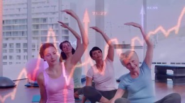 Dersi takip eden kadınlar, fitness paspaspaslarına yan oturarak esneme hareketleri, nabız örtüsü rehberliği. Grup, yoga, stüdyo, gün ışığı, şehir manzarası, aydınlık, sağlık