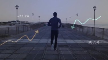 Şafak vakti deniz kenarında koşuya çıkan koşucu, deniz mavisi-sarı grafiklerle fitness performans ölçümlerini izliyor. Sporcu, açık hava, minimalist, sağlık, teknoloji, yenilik, fitness