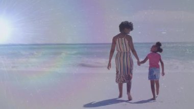 Afrika kökenli Amerikalı kadın ve kızının kumsalda yürüdüğü animasyonlar. Yaşam tarzı, aile ve ışık konsepti dijital olarak oluşturulmuş video.