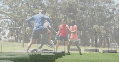 Açık havada egzersiz yapmak, çimenli alanda hareketli bir grupla lastiklerin üzerinden atlamak. Fitness, takım çalışması, egzersiz, takım çalışması, eğitim, acemi birliği