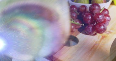 Mutfak masasındaki kesme tahtasının üzerinde kırmızı üzüm kümesi, lens fişeği ve kase, kopyalama alanı görülüyor. Stilllife, fruit, rustic, sunlit, enerjik, tahıl, doku
