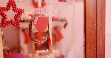 Kırmızı kalp etiketli ince bir çelenk oturma odasındaki camda pamuklu bir kurdele ve çoraplar. Şenlik, dekor, konfor, bokeh, pencere, don, süs