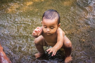 Küçük şirin bebek nehir suyunda oynuyor. Orman nehrinde eğlenen çocuk portresi. Küçük komik çocuk suda oynuyor. Baby Boy Resim Depolama.
