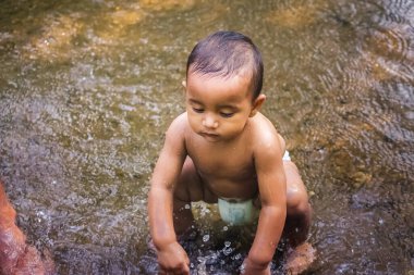 Küçük şirin bebek nehir suyunda oynuyor. Orman nehrinde eğlenen çocuk portresi. Küçük komik çocuk suda oynuyor. Baby Boy Resim Depolama.