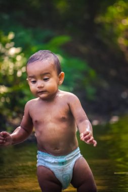 Küçük şirin bebek nehir suyunda oynuyor. Orman nehrinde eğlenen çocuk portresi. Küçük komik çocuk suda oynuyor. Baby Boy Resim Depolama.