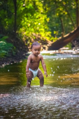 Küçük şirin bebek nehir suyunda oynuyor. Orman nehrinde eğlenen çocuk portresi. Küçük komik çocuk suda oynuyor. Baby Boy Resim Depolama.