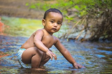 Küçük şirin bebek nehir suyunda oynuyor. Orman nehrinde eğlenen çocuk portresi. Küçük komik çocuk suda oynuyor. Baby Boy Resim Depolama.