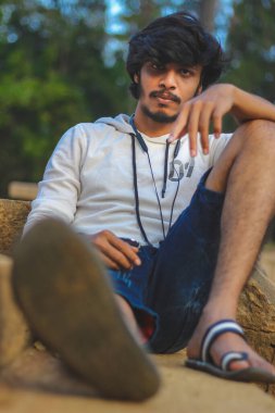 Beyaz Kapüşonlu Tişörtlü Yakışıklı Yakışıklı Yakışıklı Erkek Açık Doğa Arkaplanında Üç Dördüncü Pist Pantolonu Var. Asyalı Hintli erkek modeli. Model Moda Adamları.