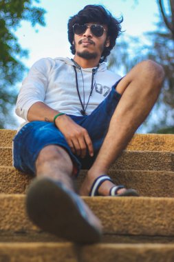 Beyaz Kapüşonlu Tişörtlü Yakışıklı Yakışıklı Yakışıklı Erkek Açık Doğa Arkaplanında Üç Dördüncü Pist Pantolonu Var. Asyalı Hintli erkek modeli. Model Moda Adamları.