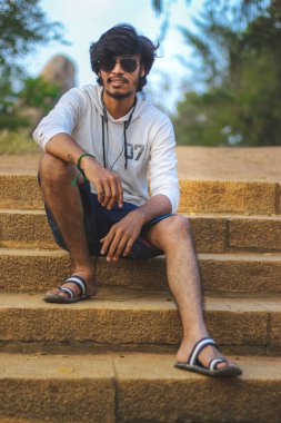 Beyaz Kapüşonlu Tişörtlü Yakışıklı Yakışıklı Yakışıklı Erkek Açık Doğa Arkaplanında Üç Dördüncü Pist Pantolonu Var. Asyalı Hintli erkek modeli. Model Moda Adamları.