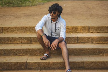 Beyaz Kapüşonlu Tişörtlü Yakışıklı Yakışıklı Yakışıklı Erkek Açık Doğa Arkaplanında Üç Dördüncü Pist Pantolonu Var. Asyalı Hintli erkek modeli. Model Moda Adamları.