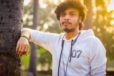 Beyaz kapüşonlu tişörtlü seksi yakışıklı erkekler doğa arka planında poz veriyor. Asyalı Hintli erkek modeli. Model Moda Adamları.