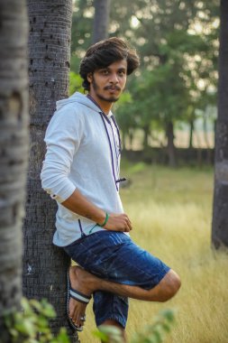 Beyaz Kapüşonlu Tişörtlü Yakışıklı Yakışıklı Yakışıklı Erkek Açık Doğa Arkaplanında Üç Dördüncü Pist Pantolonu Var. Asyalı Hintli erkek modeli. Model Moda Adamları.