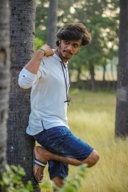 Beyaz Kapüşonlu Tişörtlü Yakışıklı Yakışıklı Yakışıklı Erkek Açık Doğa Arkaplanında Üç Dördüncü Pist Pantolonu Var. Asyalı Hintli erkek modeli. Model Moda Adamları.