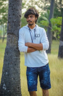 Beyaz Kapüşonlu Tişörtlü Yakışıklı Yakışıklı Yakışıklı Erkek Açık Doğa Arkaplanında Üç Dördüncü Pist Pantolonu Var. Asyalı Hintli erkek modeli. Model Moda Adamları.