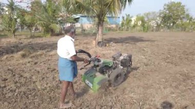 Chennai, Hindistan - 11 Şubat 2021: Kıdemli çiftçi tarım için topraklarını sürmek için eski bir traktör kullanıyor. Çiftçilerin Toprağı Sürme Gününde Mouldboard Plough ile Traktör Kullanımı.