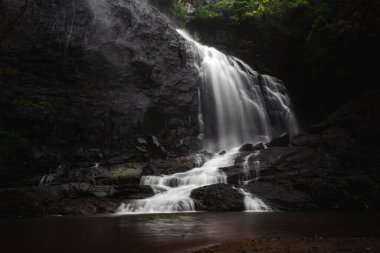Güzel şelale manzarası. Soğuk su havuzuna akan uzun bir şelale manzarası. Tropikal yağmur ormanlarında saklı güzel bir şelale. Yavaş deklanşör hızı, hareket fotoğrafçılığı.