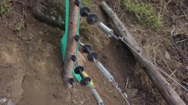 Elektrikli çit kapısının kapatılması tarım arazilerinin vahşi hayvanlardan korunmasını sağlar. Çitin gergin yayı. Elektrikli tellere bağlı metalik gerilim yayı.