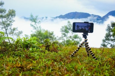 Akıllı cep telefonu güzel bir manzarada mini tripod standında duruyor. Mobil Tripod Stok resimleri.