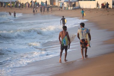 Kovalam, Chennai, Tamilnadu, Hindistan 9 Ağustos 2021 Hintli genç sörfçü ve plaj dalgalarında pratik yapıyor..