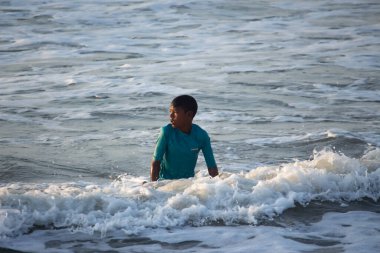 Kovalam, Chennai, Tamilnadu, Hindistan 9 Ağustos 2021 Hintli genç sörfçü ve plaj dalgalarında pratik yapıyor..