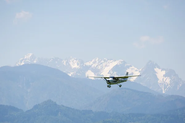 Piccolo aeroplano che vola, montagne su sfondo Foto Stock Royalty Free