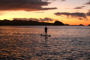 Ayakta duran genç bir kızın silüet fotoğrafı. Aktif tatiller, sahilde hayat. Filipinler