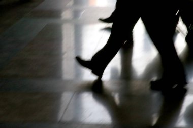 Yandan yürüyen dört bacaklı siyah siluetler. Parlak arka planda yürüyorlar, İtalya Milan.