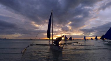 Gün batımı manzarası. Boracay adasının kıyısında bir yelkenli. Filipinler