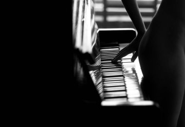 Genç ve çekici bir kız piyano çalıyor, çıplak bir figür. 