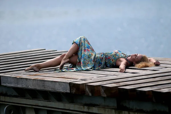 İskelede deniz manzarası olan seksi güzel bir kadın. Tatil görüşü