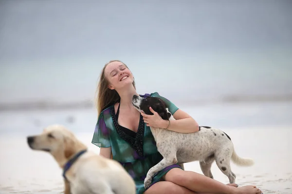遊び心のある若い犬と海の海岸に座っている美しい女性の肖像画 — ストック写真