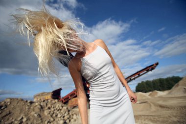 Endüstriyel bir alanda süzülen saçları olan güzel sarışın bir kız.