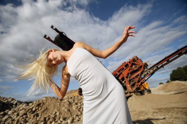 Endüstriyel bir alanda süzülen saçları olan güzel sarışın bir kız.