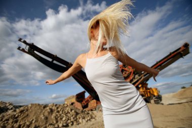 Endüstriyel bir alanda süzülen saçları olan güzel sarışın bir kız.