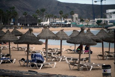 Tropik bir sahilde boş güneşli yataklar, deniz kenarında kumlu plajlar. Yaz tatili ve tatil fikri turizm, salgın, karantina, Tenerife 