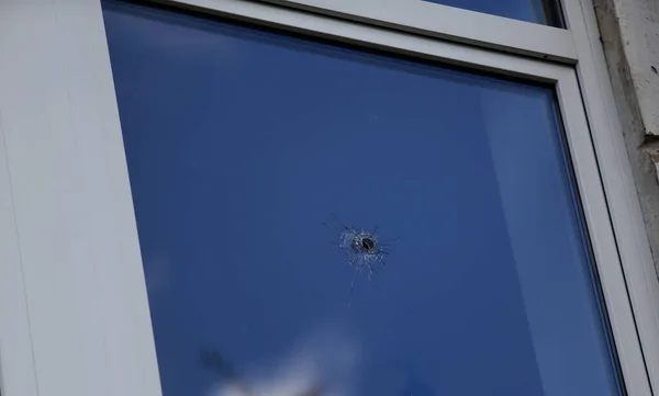 A shot from a firearm, a bullet-pierced room window