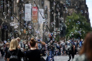 Bir sokak sanatçısı şehir merkezinde yüzlerce küçük, küçük ve büyük kabarcık patlatır. Edinburgh, İskoçya 1907 2019