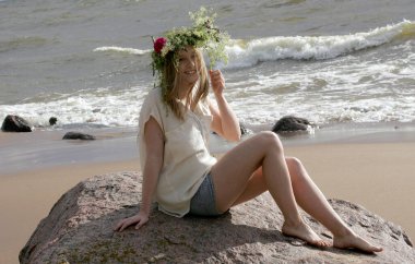 Gün batımında kumsalda çiçek tacını takmış genç bir kadının gülümsemesini ve eğlenmesini sağla.